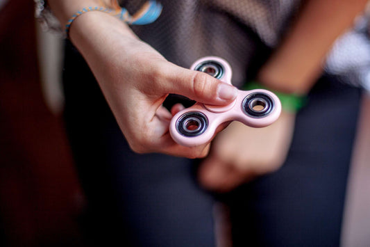Close-up of a hand spinning a fidget spinner, illustrating the use of fidget toys for managing anxiety and ADHD symptoms, highlighting their practical benefits.