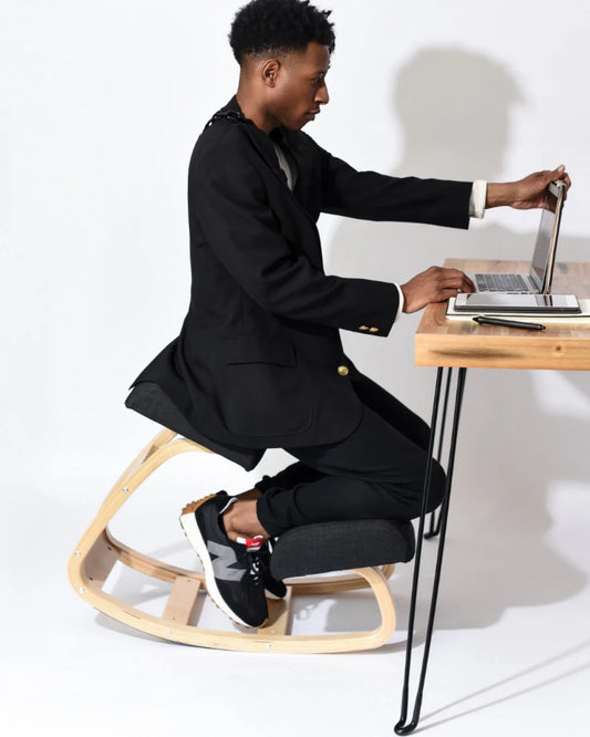 Businessman using an ergonomic kneeling chair at his office desk, showcasing correct posture to alleviate lower back pain, demonstrating the effectiveness of kneeling chairs for back health.