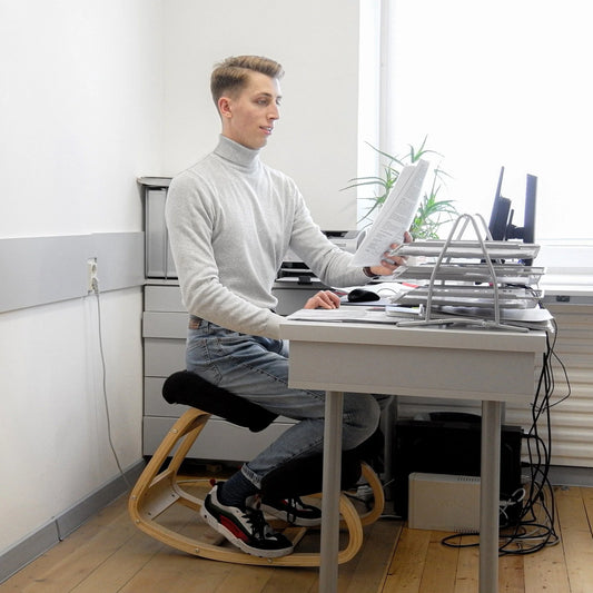 Man sitting on ergonomic kneeling chair while working in office