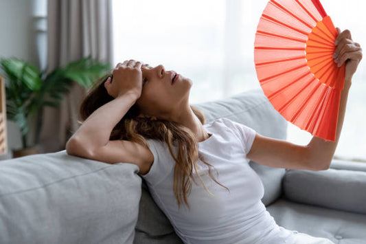 Woman unable to sleep due to high heat, visibly uncomfortable in a warm bedroom setting, illustrating the need for a cool sleeping environment without air conditioning.